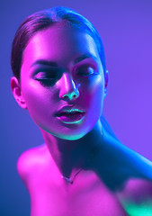 Wall Mural - High Fashion model woman in colorful bright neon lights posing in studio, night club. Portrait of beautiful girl in UV. Art design colorful make up. On colourful vivid background,