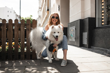 Beautiful girl with a  Cute  beautiful  Samoyed dog in a park  with owner outdoors