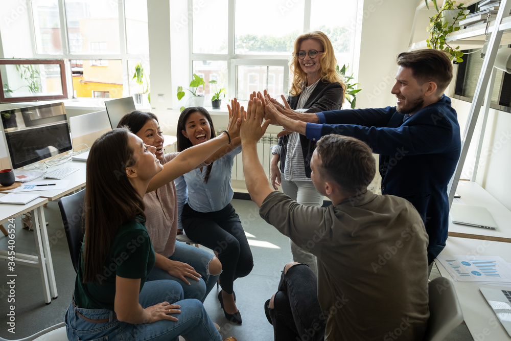 Multiracial employees team with male leader, coach giving high five at company meeting, female teacher with interns celebrating achievement, corporate success of teamwork, team building activity. - obrazy, fototapety, plakaty 