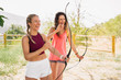 © ManuPadilla - Two beautiful young women having fun and smiling practicing archery in the field. Archery, Sport, Recreation Concept.