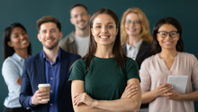Close Up Headshot Portrait Of Happy Businesswoman Hands Crossed Posture. Different Age And Ethnicity Businesspeople Standing Behind Of Female Company Chief Business. Leader Of Multi-ethnic Team