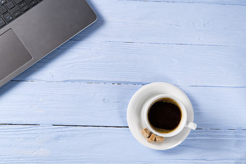 Poster - Laptop with cup of coffee on light blue old wooden table. Notebook with cup of fresh coffee in home office. Working from home concept