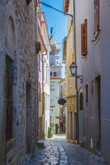 Empty street in Krk town on the island Krk in Croatia. Bell tower of the cathedral in the background.