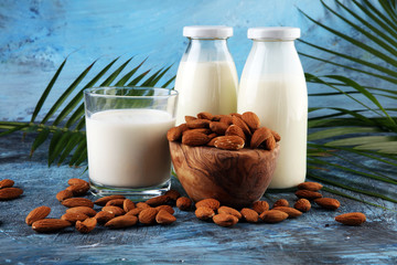 Wall Mural - almond milk with fresh nuts and palm leaves on rustic background.