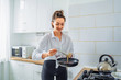 © Daria - Woman pours the dough into a pan to cook homemade fried banana pancakes. Hobby in a beautiful bright kitchen. The economic wife is waiting for her husband from work with delicious tasty food
