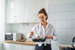 © Daria - Woman pours the dough into a pan to cook homemade fried banana pancakes. Hobby in a beautiful bright kitchen. The economic wife is waiting for her husband from work with delicious tasty food