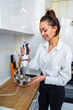 © Daria - Attractive girl preparing dough in a food processor while standing in a bright kitchen. Mixing dough with hand mixer on kitchen table background with cooking ingredients
