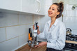 © Daria - Attractive girl preparing dough in a food processor while standing in a bright kitchen. Mixing dough with hand mixer on kitchen table background with cooking ingredients