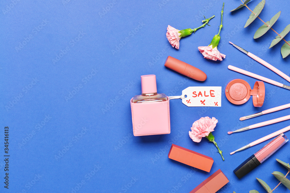 Bottle of perfume with makeup cosmetics on color background