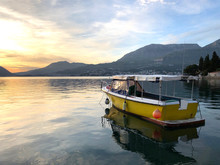Yellow Boat On The Water In The Bay Against The Backdrop Of Mountains At Sunset