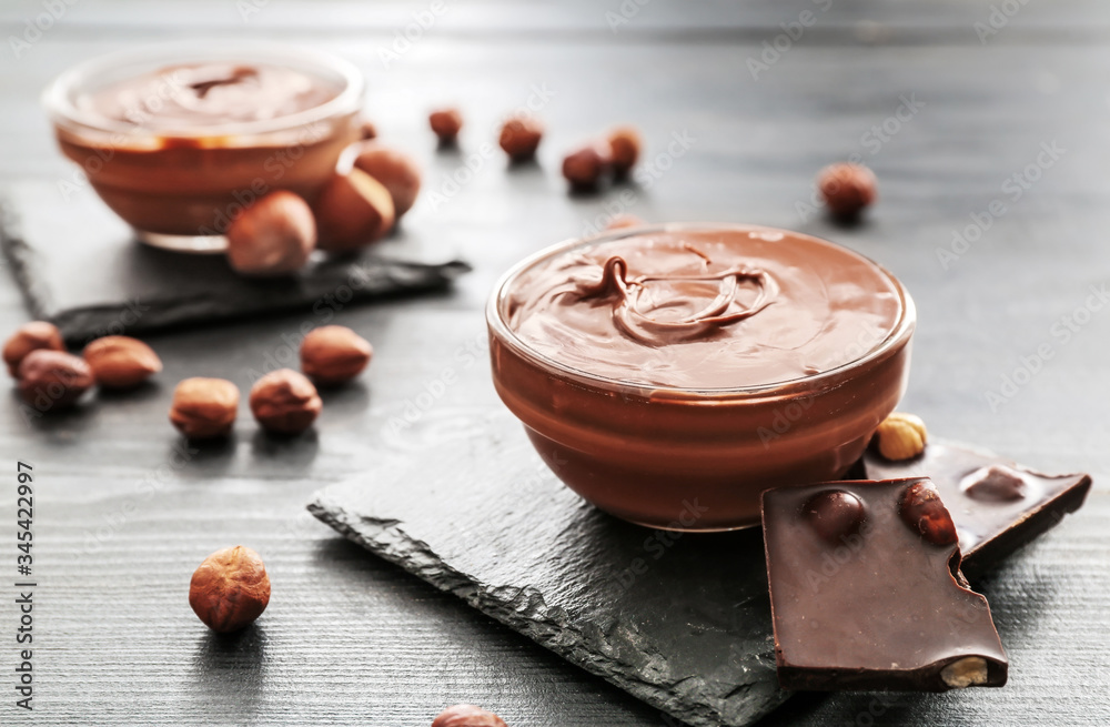 Bowl with tasty chocolate paste and hazelnuts on table