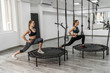 © Тарас Нагирняк - Photo of two active girls and fitness trainer in sport clothes doing exercises for stretching with trampoline during training in gym