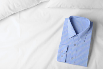 Stylish light blue shirt on bed, top view with space for text. Dry-cleaning service