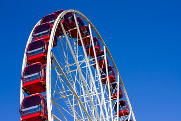 Red and white ferris wheel on a blue sky