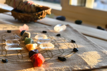 An Close Up Image Of Chakra Balancing Crystals On A Wooden Table With Glowing Evening Sunlight Warming The Crystals. 