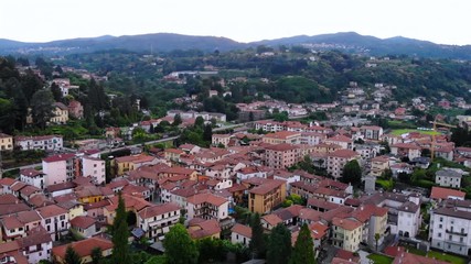 Aufkleber - aerial view on small town surrounded green landscape and seaside on the background mountains