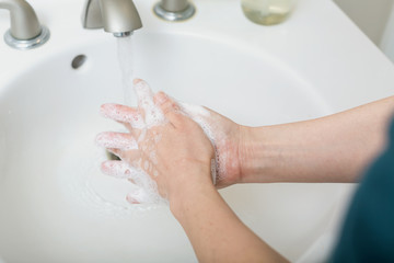 Wall Mural - Person washing their hands at with soap and water for coronavirus prevention