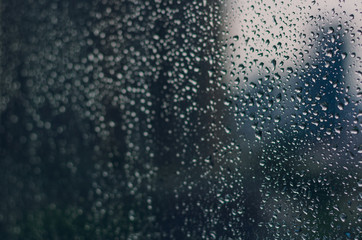 Wall Mural - Blurred and focus of rain drop on glass window in monsoon season with blurred building background for abstract and background concept.