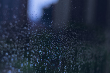 Wall Mural - Blurred and focus of rain drop on glass window in monsoon season with blurred building background for abstract and background concept.