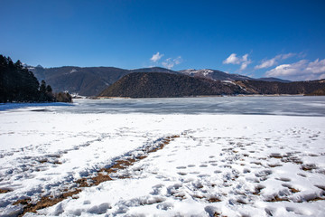 Wall Mural - Potatso National Park or Pudacuo National Park during winter with mountain and frozen lake scenery with snow covered ground