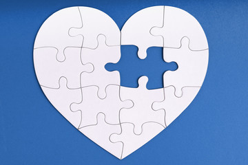 Love, charity, donation, helping concept. Missing piece of jigsaw puzzle in heart shape on blue. Looking for love partner. Uncompleted puzzle. Relationship. Mental health problems, heartache