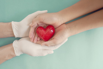 Wall Mural - Doctor hands with medical gloves holding child hands and red heart, health insurance, donation, charity during covid-19 coronavirus pandemic, saving life, thank you and appreciation to doctor