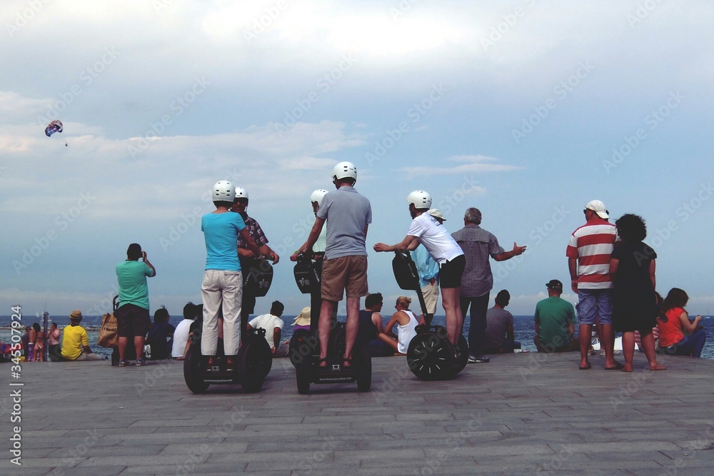 Rear View Of People On Segways At Beach - obrazy, fototapety, plakaty 