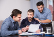 © JackF - Two positive men helping friend with documents at table