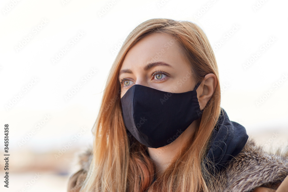 health, safety and pandemic concept - young woman wearing black face protective reusable barrier mask outdoors - obrazy, fototapety, plakaty 
