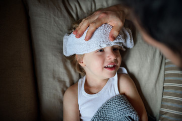 Wall Mural - Unrecognizable father checking on small sick son lying in bed indoors at home.