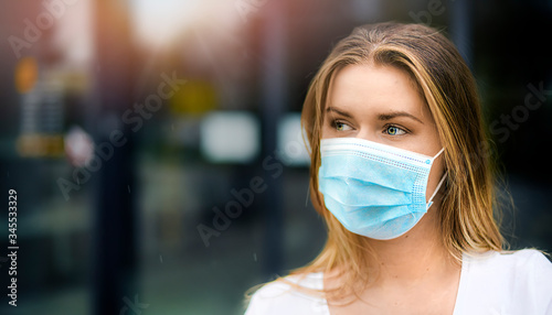Fotomural Epidemic Corona Virus masked girl on the blur background of the city