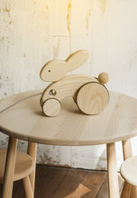 Photo Of A Wooden Rabbit On Wheels Of Beech On Table.A Toy For Entertaining Children And Resting Parents