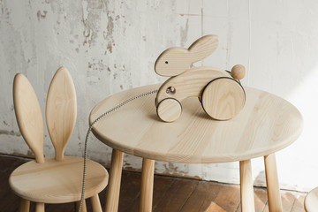 Photo of a wooden rabbit on wheels of beech on table.A toy for entertaining children and resting parents