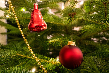 Red christmas ornaments in a tree with lights and a golden chain