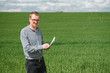 © Serhii - An agronomist investigates the ripening process of young wheat in the field. Agricultural business concept. The farmer works on a wheat field and inspects the quality of wheat sprouts.