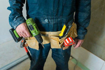 Worker holds construction tools in his hands.