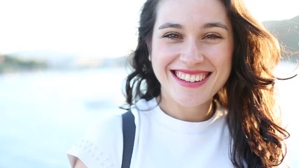 Wall Mural - Happy young beautiful woman smiling near the sea in summer