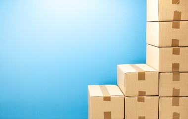 Wall Mural - Cardboard boxes steps up for delivery or moving. Stack of boxes and blue background. Copy space for text