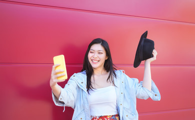 Wall Mural - Happy Asian girl taking selfie with mobile smart phone outdoor - Young influencer having fun with new trends social networks apps - Millennial generation lifestyle people technology