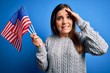 © Krakenimages.com - Young patriotic woman holding usa flag on independence day 4th of july over blue background stressed with hand on head, shocked with shame and surprise face, angry and frustrated. Fear and upset.