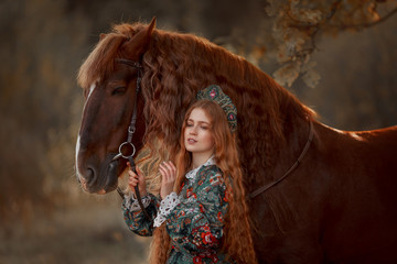 Wall Mural - Beautiful long-haired blonde young woman in national russian style with red Vladimir draft horse in autumn forest