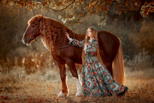 Beautiful Long-haired Blonde Young Woman In National Russian Style With Red Vladimir Draft Horse In Autumn Forest