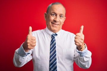 Sticker - Senior handsome businessman wearing elegant tie standing over isolated red background success sign doing positive gesture with hand, thumbs up smiling and happy. Cheerful expression and winner gesture