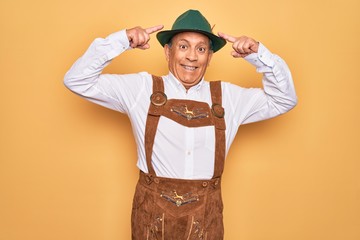 Poster - Senior grey-haired man wearing german traditional octoberfest suit over yellow background smiling pointing to head with both hands finger, great idea or thought, good memory