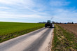 © Martin - road along which goes an old tractor on wood with green fields around and blue sky