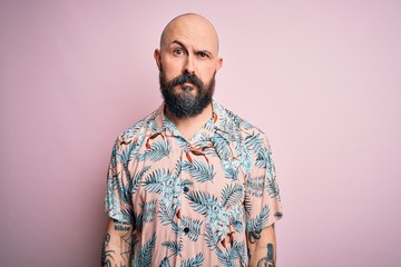 Poster - Handsome bald man with beard and tattoo wearing casual floral shirt over pink background looking sleepy and tired, exhausted for fatigue and hangover, lazy eyes in the morning.