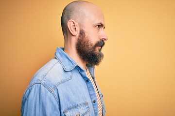 Poster - Handsome bald man with beard wearing casual denim jacket and striped t-shirt looking to side, relax profile pose with natural face with confident smile.