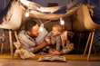 © Seventyfour - Young parents having fun with their little daughter in handmade tent at home in evening, horizontal shot