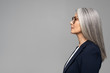 © LIGHTFIELD STUDIOS - side view of beautiful asian businesswoman with grey hair in eyeglasses isolated on grey