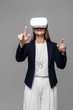 © LIGHTFIELD STUDIOS - corporate businesswoman pointing and using virtual reality headset isolated on grey